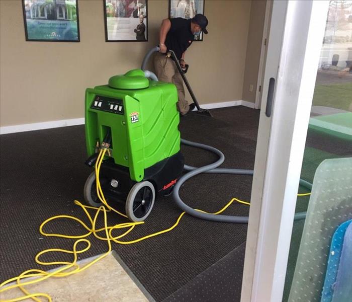 servpro employee cleaning carpets with equipment